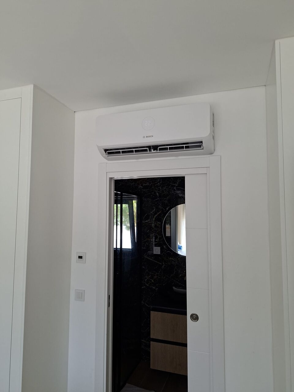 Unidade interior de ar condicionado Bosch instalada sobre porta de quarto, Quinta da Balaia, Albufeira