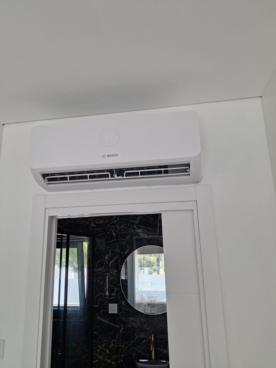 Unidade interior de ar condicionado Bosch instalada sobre porta de casa de banho, Quinta da Balaia, Albufeira