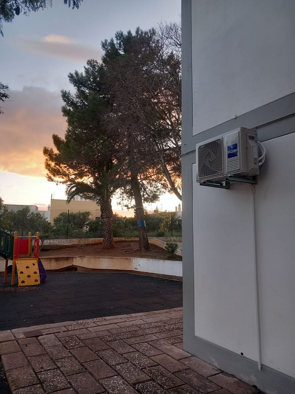 Unidade exterior de ar condicionado Haier instalada em pátio de escola primária, Portimão