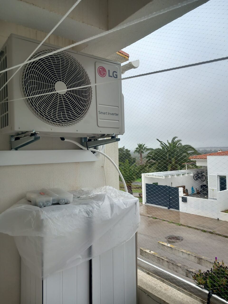 Unidade exterior de ar condicionado LG montada em varanda com vista para a rua, Portimão